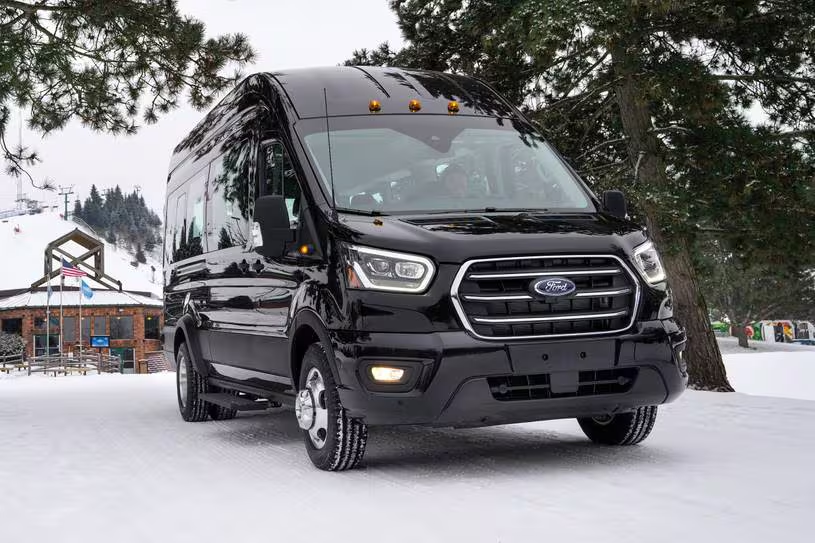 Black Ford Transit van in snowy mountain setting showcasing winter destination capability